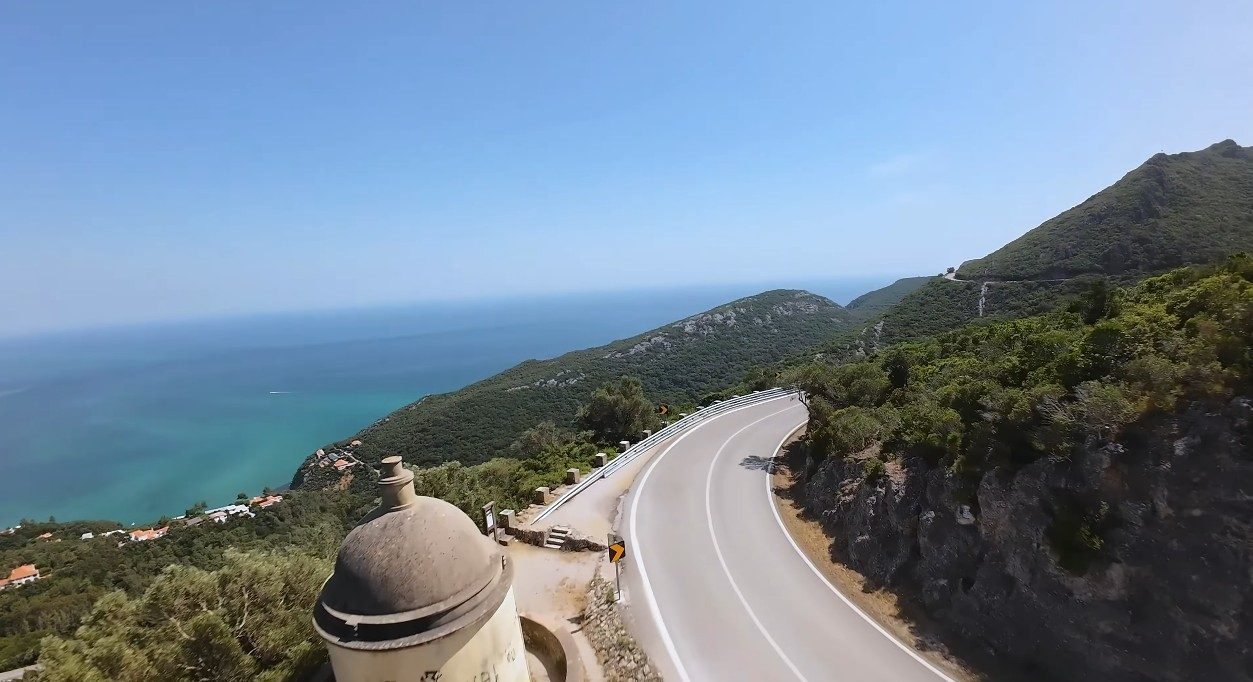 Dramatic limestone cliffs of Serra da Arrábida Natural Park dropping into crystal-clear turquoise water, viewed from above