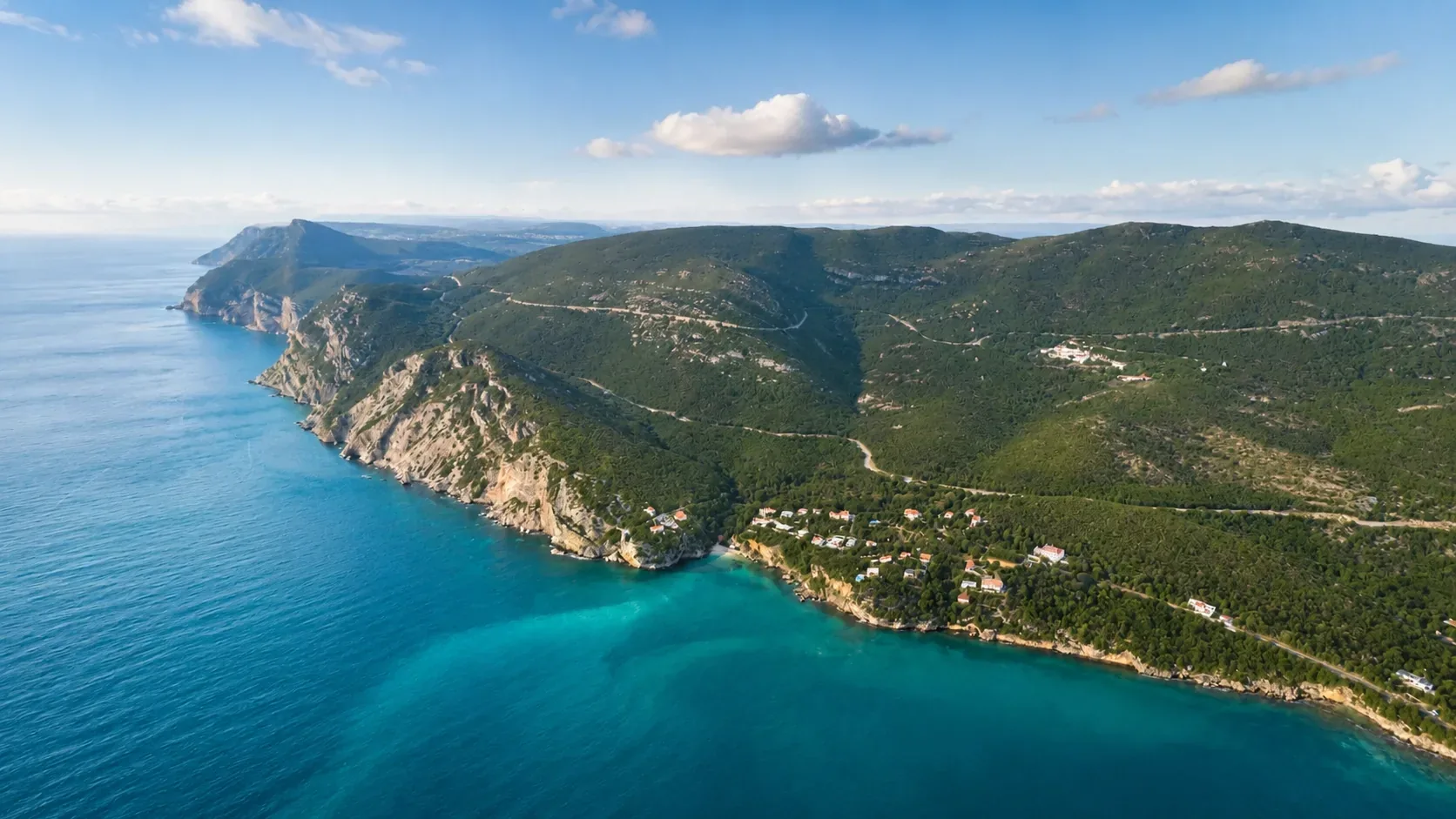 Full panoramic view of the Serra da Arrábida Natural Park coastline — turquoise water, pine-covered cliffs and the Setúbal Peninsula