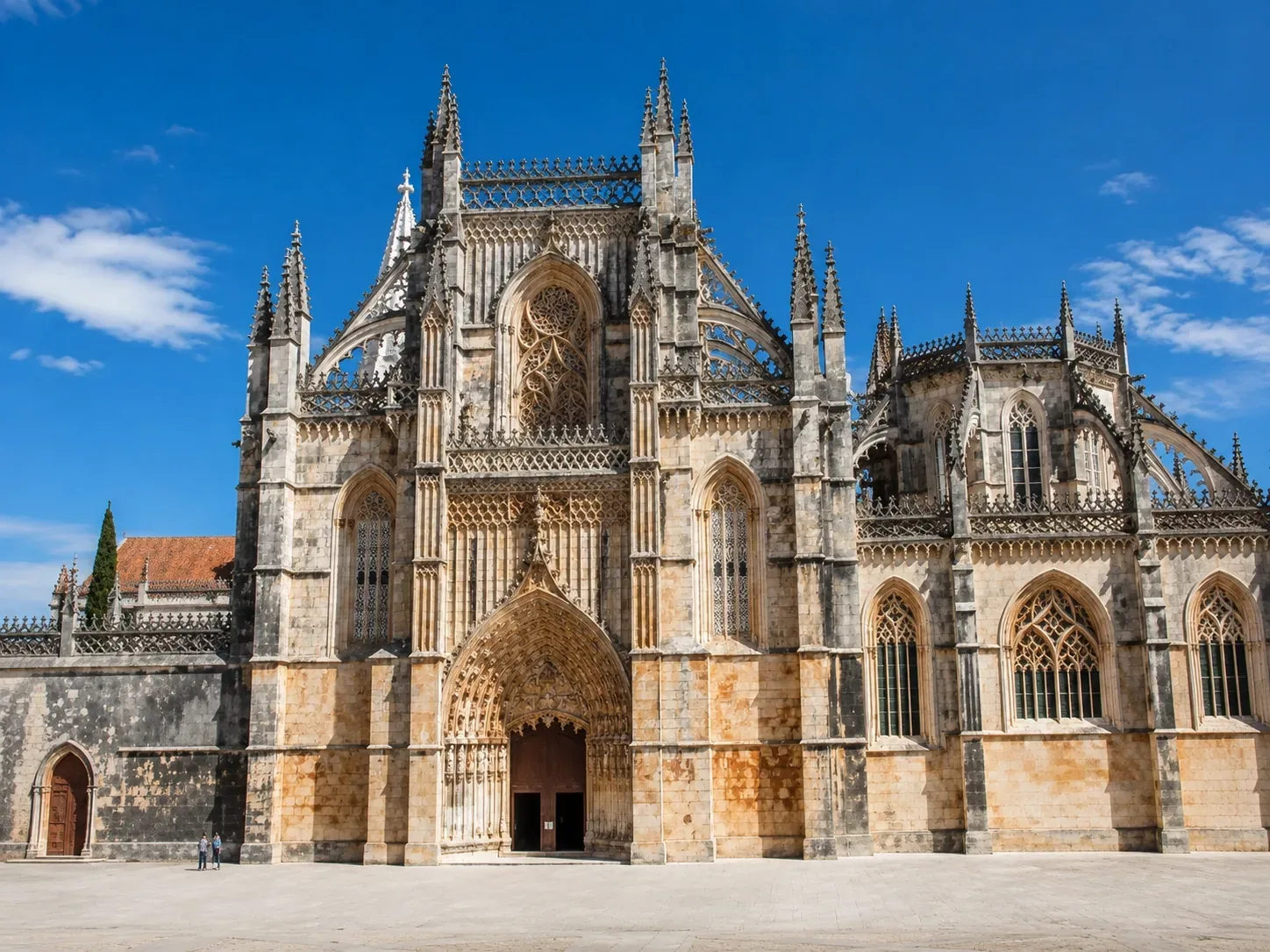 The ornate south portal and Gothic façade of Batalha Monastery — UNESCO World Heritage Site — with elaborate stone-carved pinnacles, flying buttresses and life-size statues, built to honour Portugal's victory at the 1385 Battle of Aljubarrota
