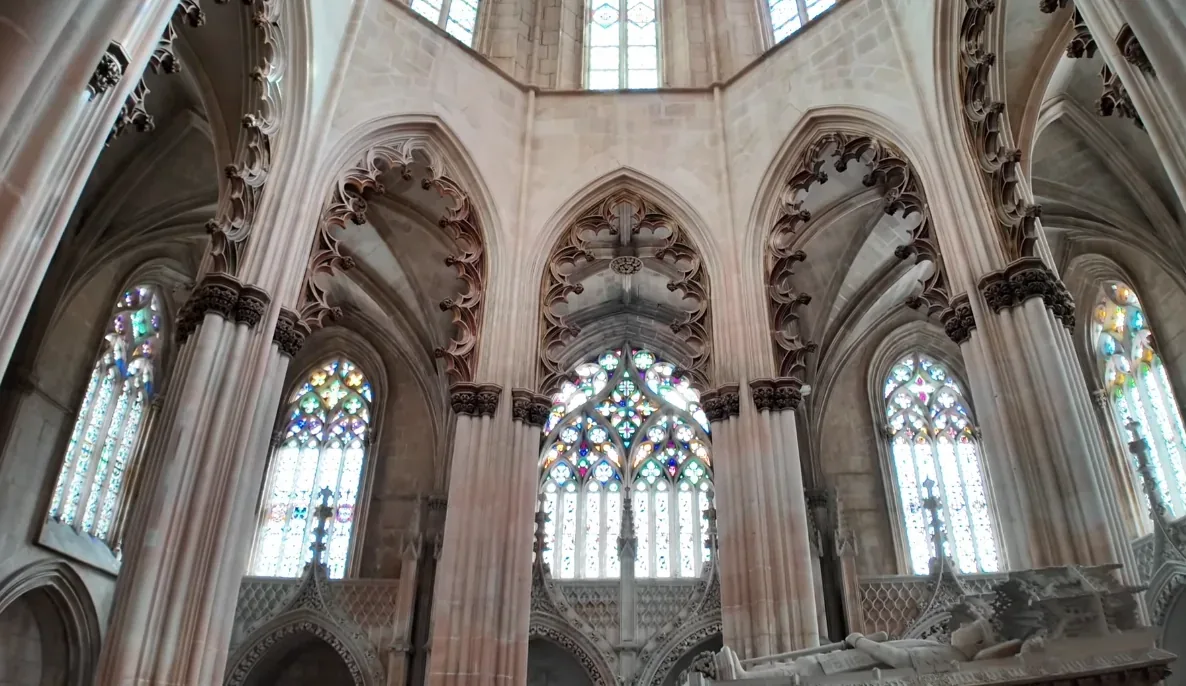 Looking up through the open sky crown of Batalha's Capelas Imperfeitas — the Unfinished Chapels roofless since 1533, with exuberantly carved Manueline stonework rising around the open octagonal rotunda in one of Portugal's most hauntingly beautiful spaces