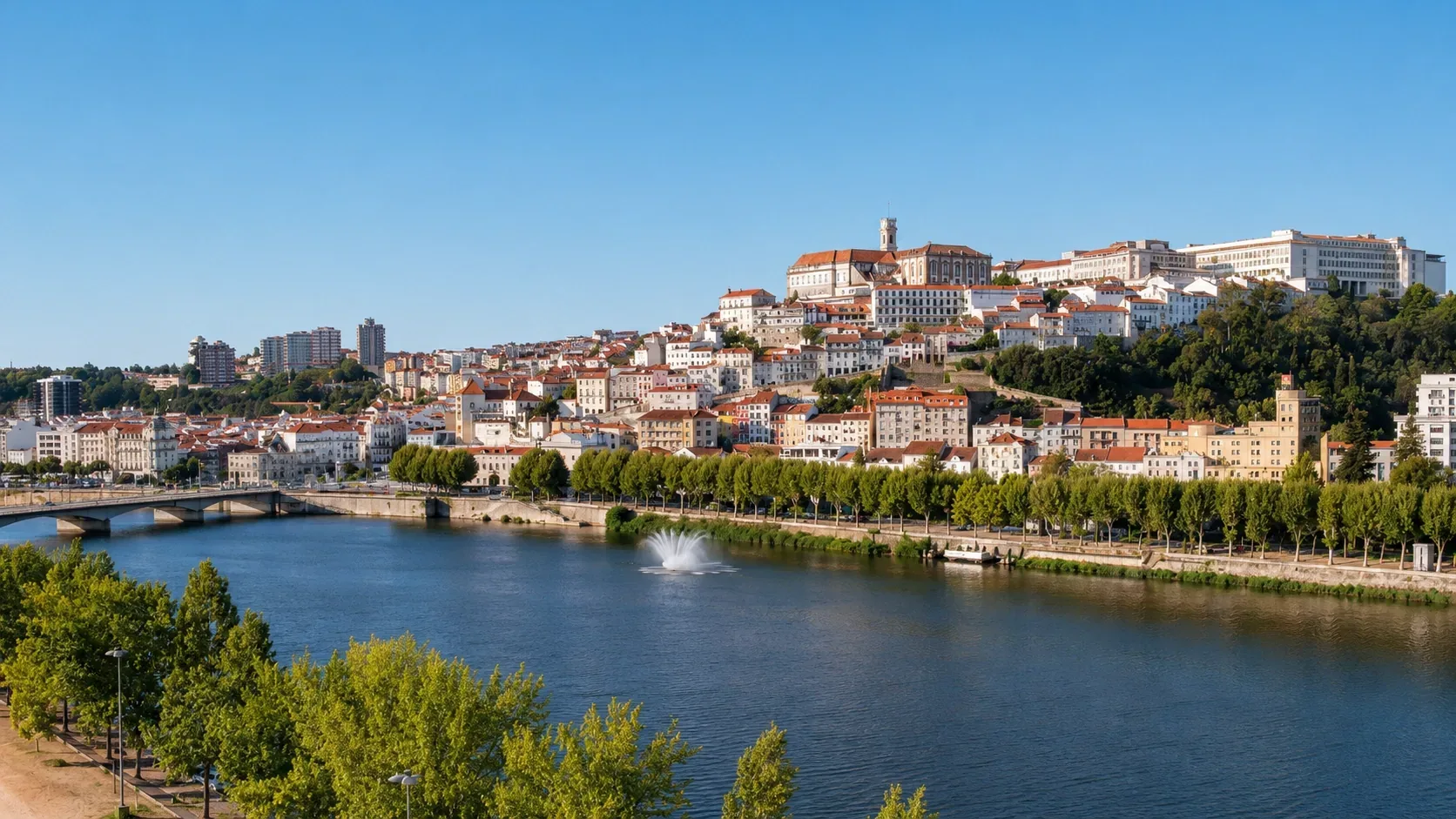 Panoramic view from the University of Coimbra terrace across the red-tiled rooftops of the city towards the Mondego River winding through the valley below — one of the finest views in Central Portugal, seen from Portugal's oldest university hill