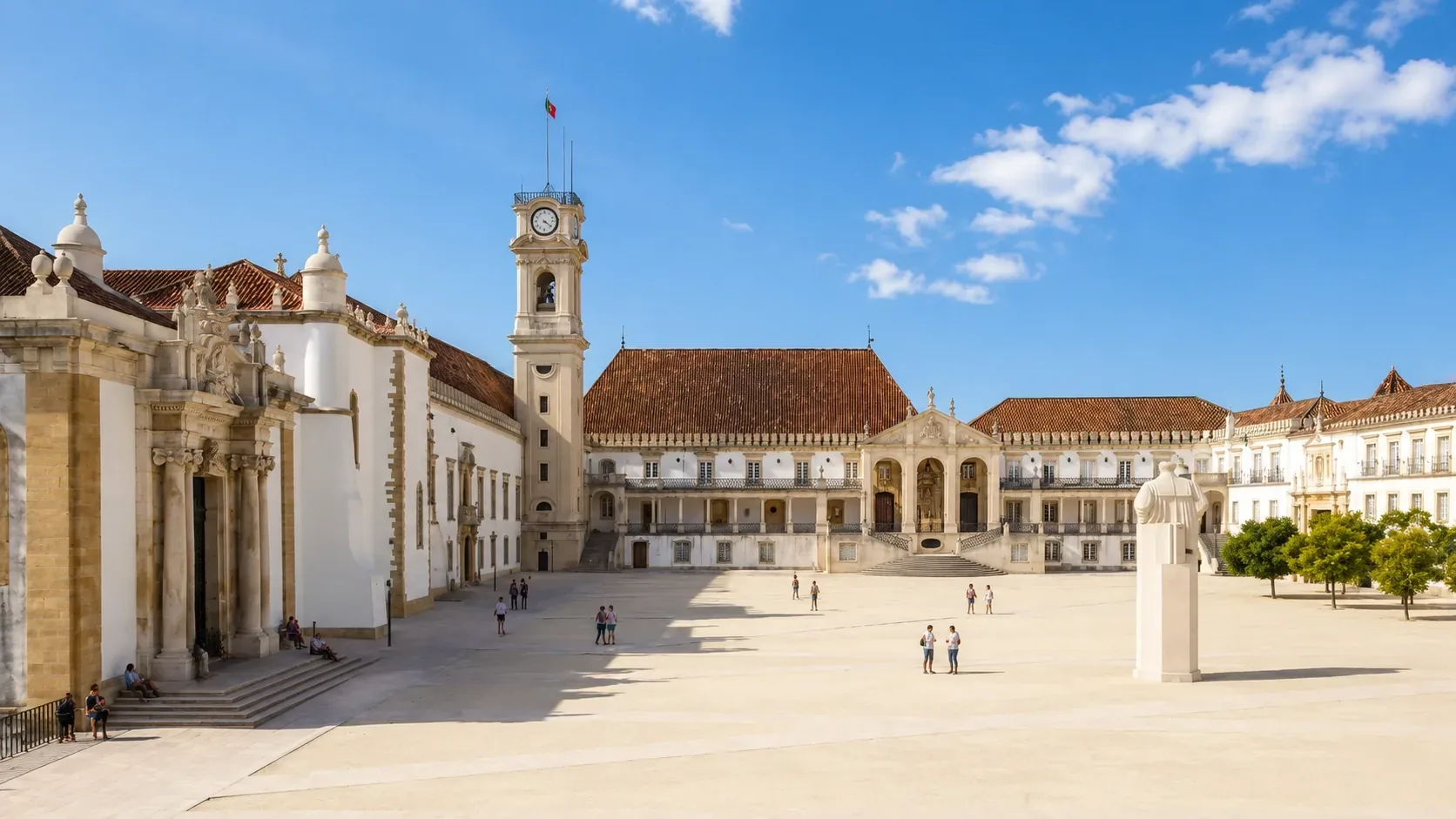 The Paço das Escolas ceremonial courtyard of the University of Coimbra — the baroque university square showing the 17th-century clock tower (A Cabra), the iron gate entrance, and the main palace facades overlooking the tiled rooftops of the city below, UNESCO World Heritage Site