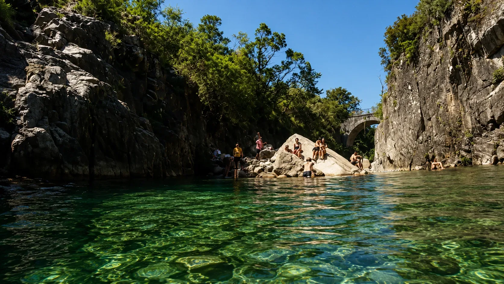 The River Homem or Cávado flowing through the interior of Peneda-Gerês National Park — clear green mountain water over granite boulders between forested riverbanks, with the deep swimming pools and cascades that make the park's rivers among the most pristine and beautiful natural swimming spots in Portugal