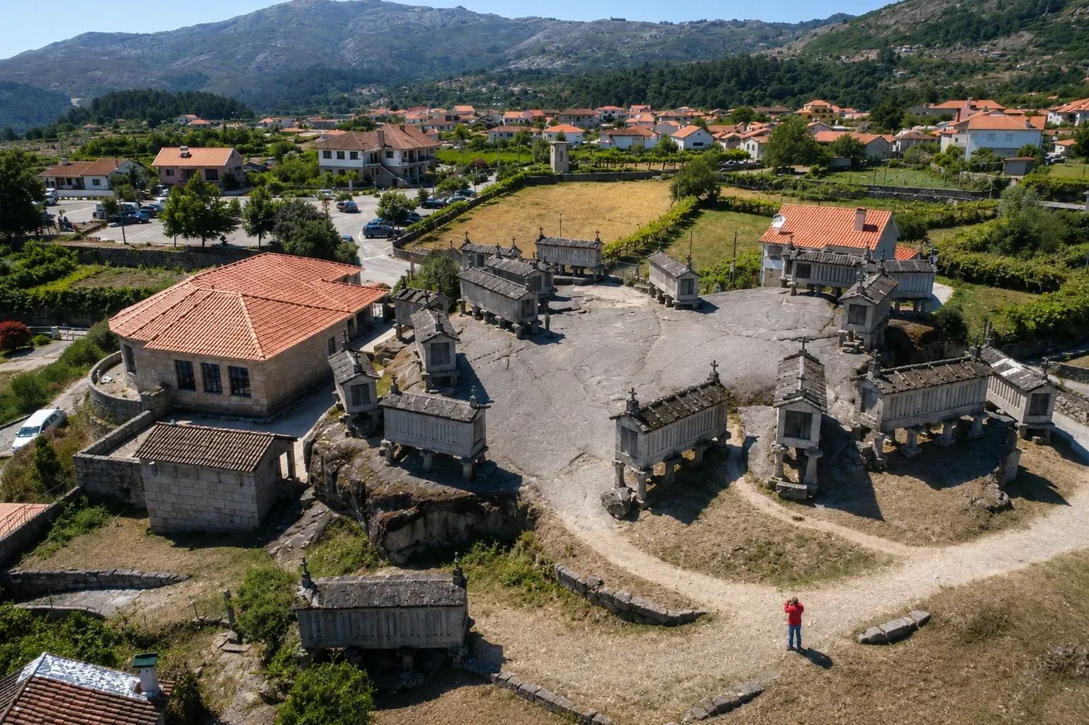 The famous espigueiros granaries of Soajo village in Peneda-Gerês — 24 traditional raised stone granaries on mushroom-shaped granite legs clustered on the village threshing floor, one of the most distinctive vernacular architectural ensembles in the Iberian Peninsula, with the granite mountain landscape of the national park behind