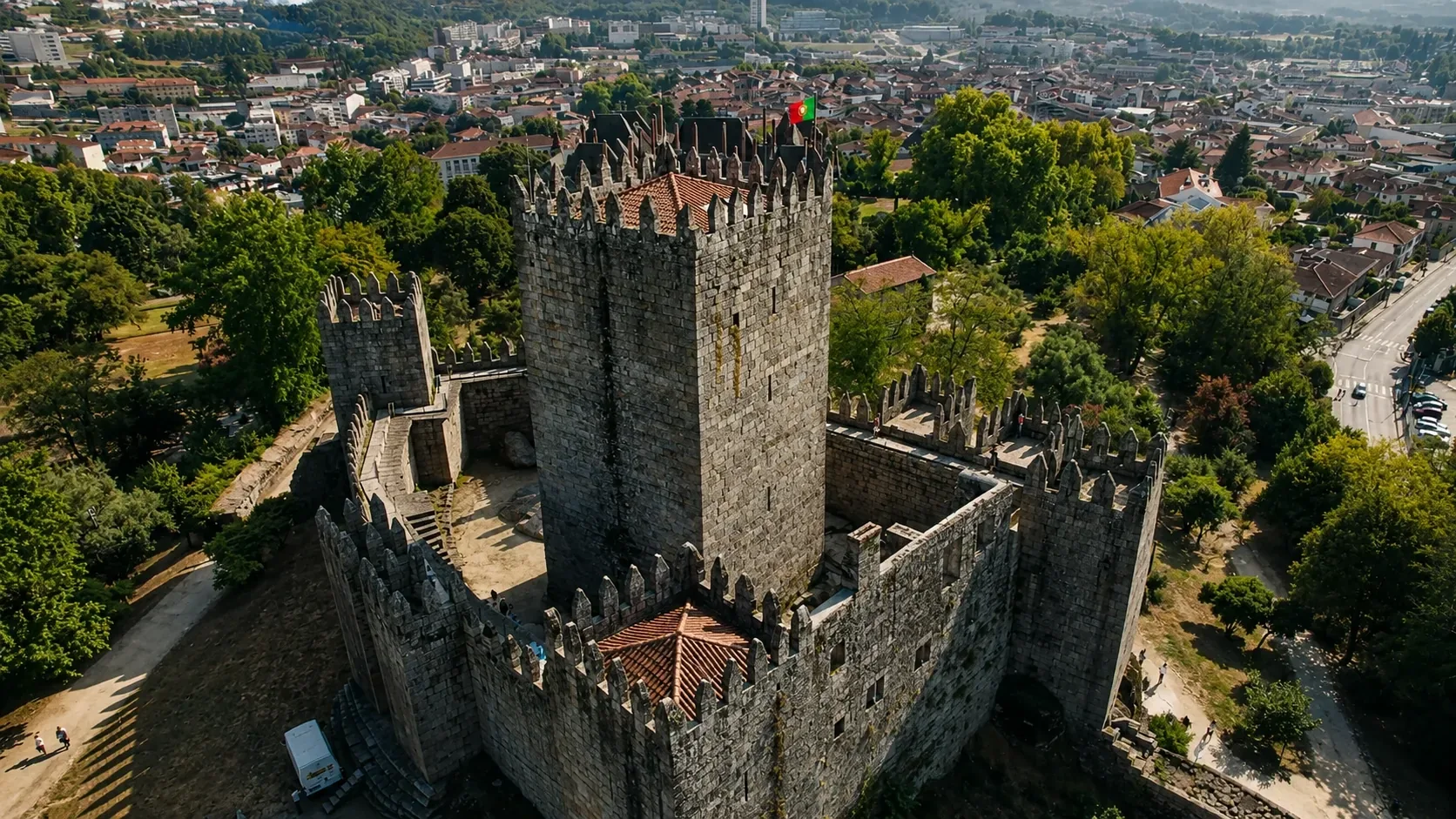 The medieval towers of Guimarães Castle (Castelo de Guimarães) rising from the granite hilltop — the 10th-century fortress with its seven square defensive towers and stone curtain wall, where Afonso Henriques, the first King of Portugal, was raised and from which he launched the military campaigns that founded the Portuguese nation in 1139