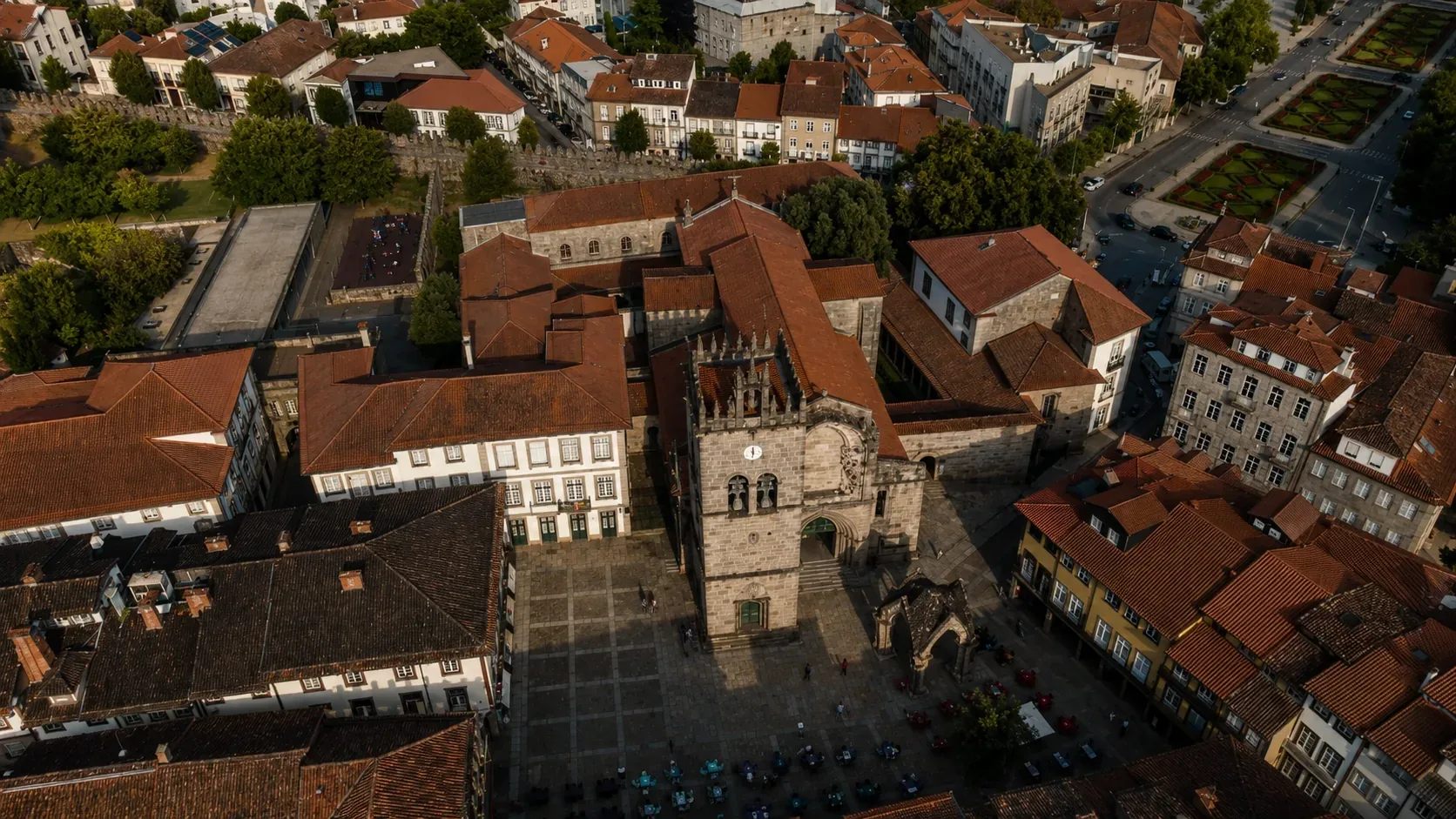 Largo da Oliveira in Guimarães — the medieval square at the heart of the UNESCO World Heritage historic centre, dominated by the Gothic stone canopy (Padrão do Salado, erected 1340) commemorating the Portuguese victory at the Battle of Rio Salado, with the Church of Our Lady of the Olive Tree behind it and the characteristic granite paving and medieval facades surrounding the square