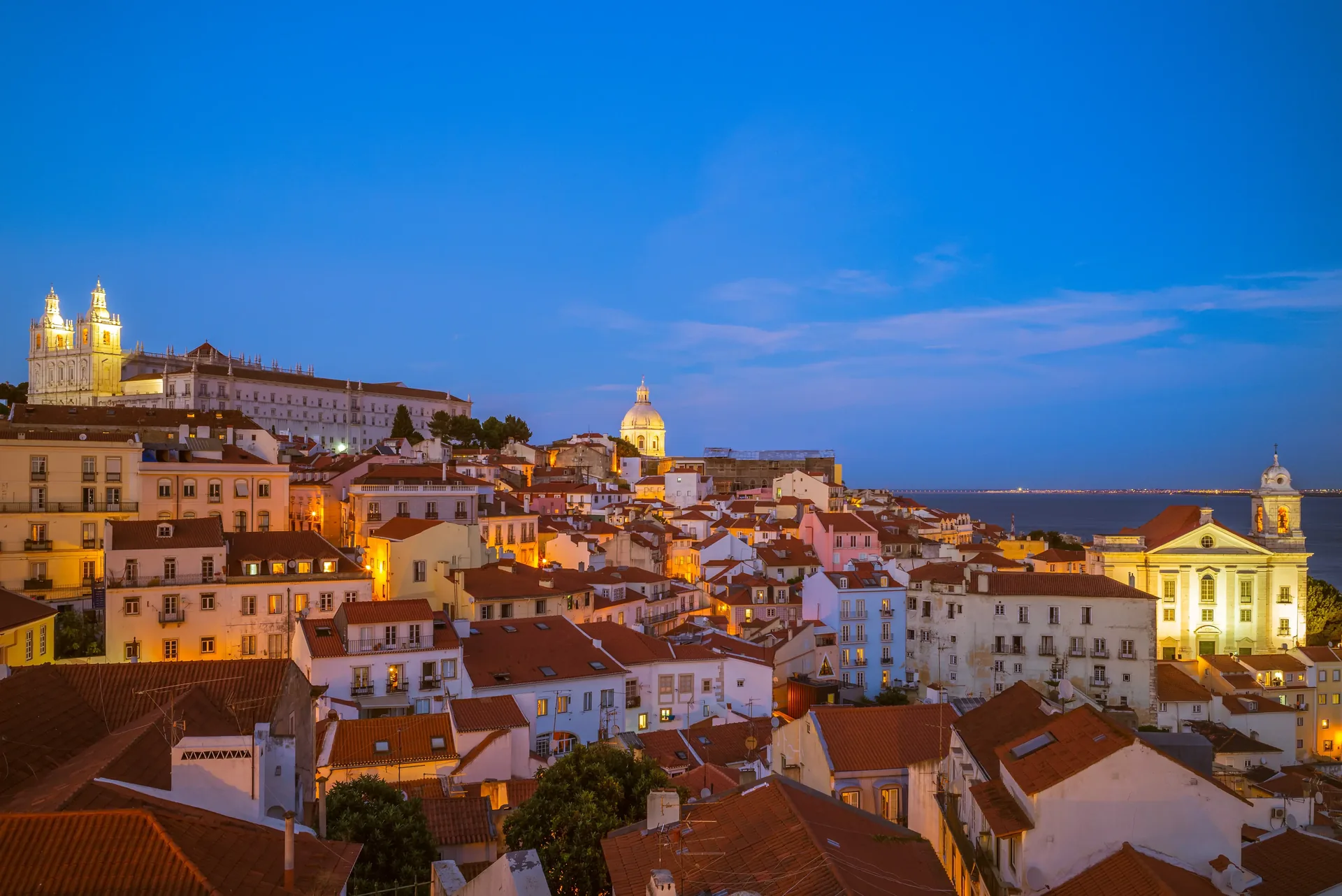 Narrow cobblestone streets and whitewashed houses of Alfama — Lisbon's oldest Moorish neighbourhood, a UNESCO-listed hillside quarter of steep lanes, colourful azulejo tiles, and hidden miradouros, birthplace of Fado music and the soul of the city