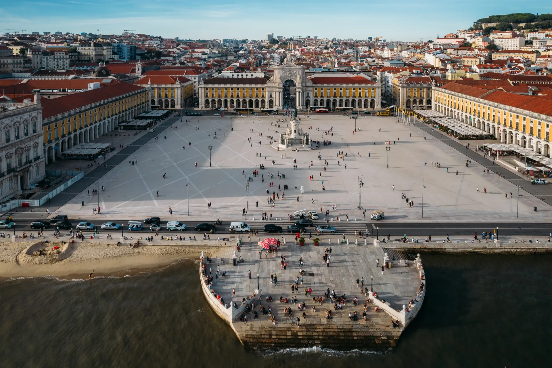 Praça do Comércio — Lisbon's grand 18th-century riverside square on the banks of the Tagus, framed by yellow arcaded government buildings and the triumphal Arco da Rua Augusta, once the ceremonial entrance to the Portuguese capital for arriving fleets
