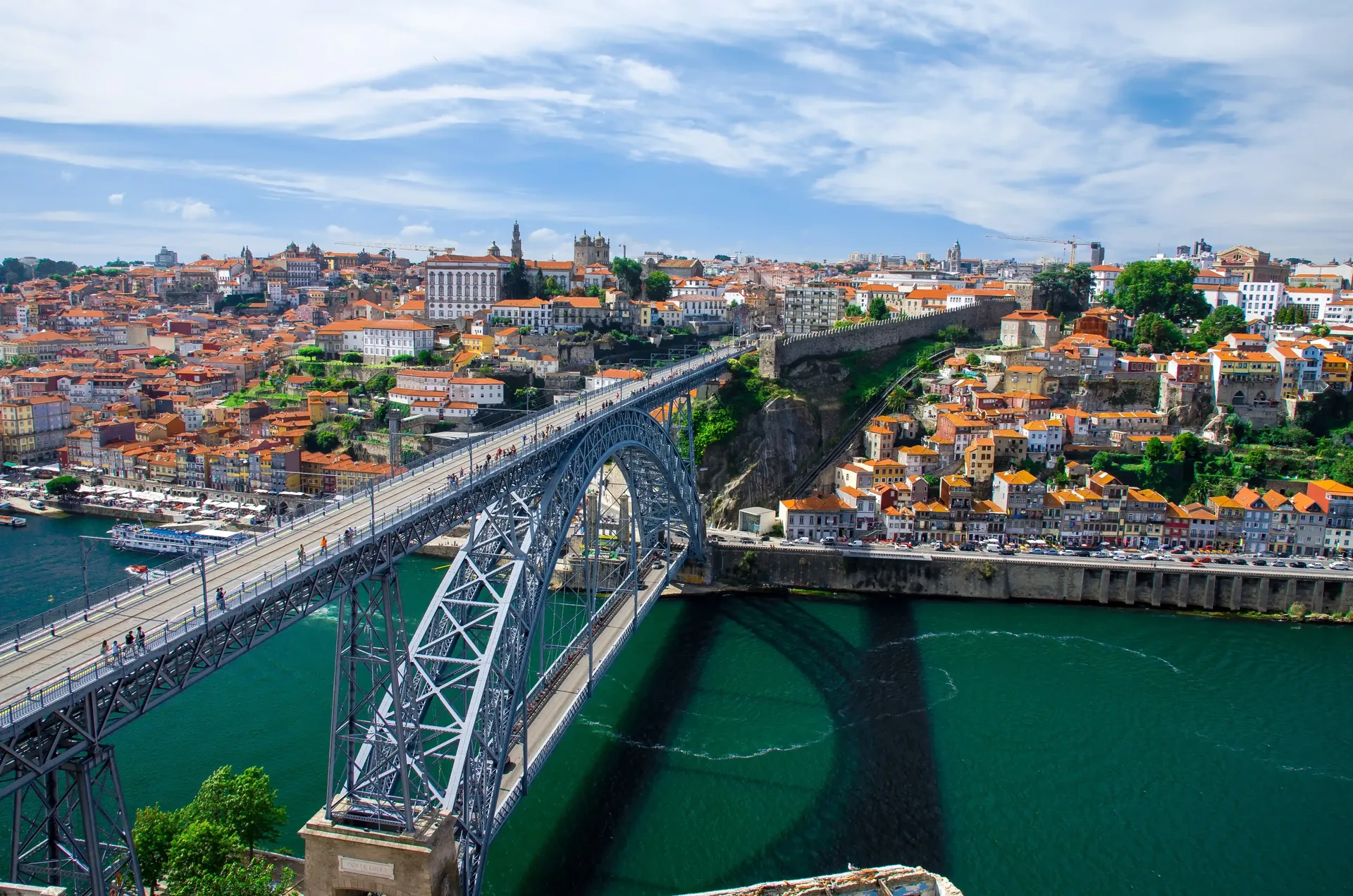 Walking the upper deck of Dom Luís I Bridge — the 172-metre upper iron walkway high above the Douro with panoramic views across both banks of Porto and Vila Nova de Gaia, shared with the metro and pedestrians