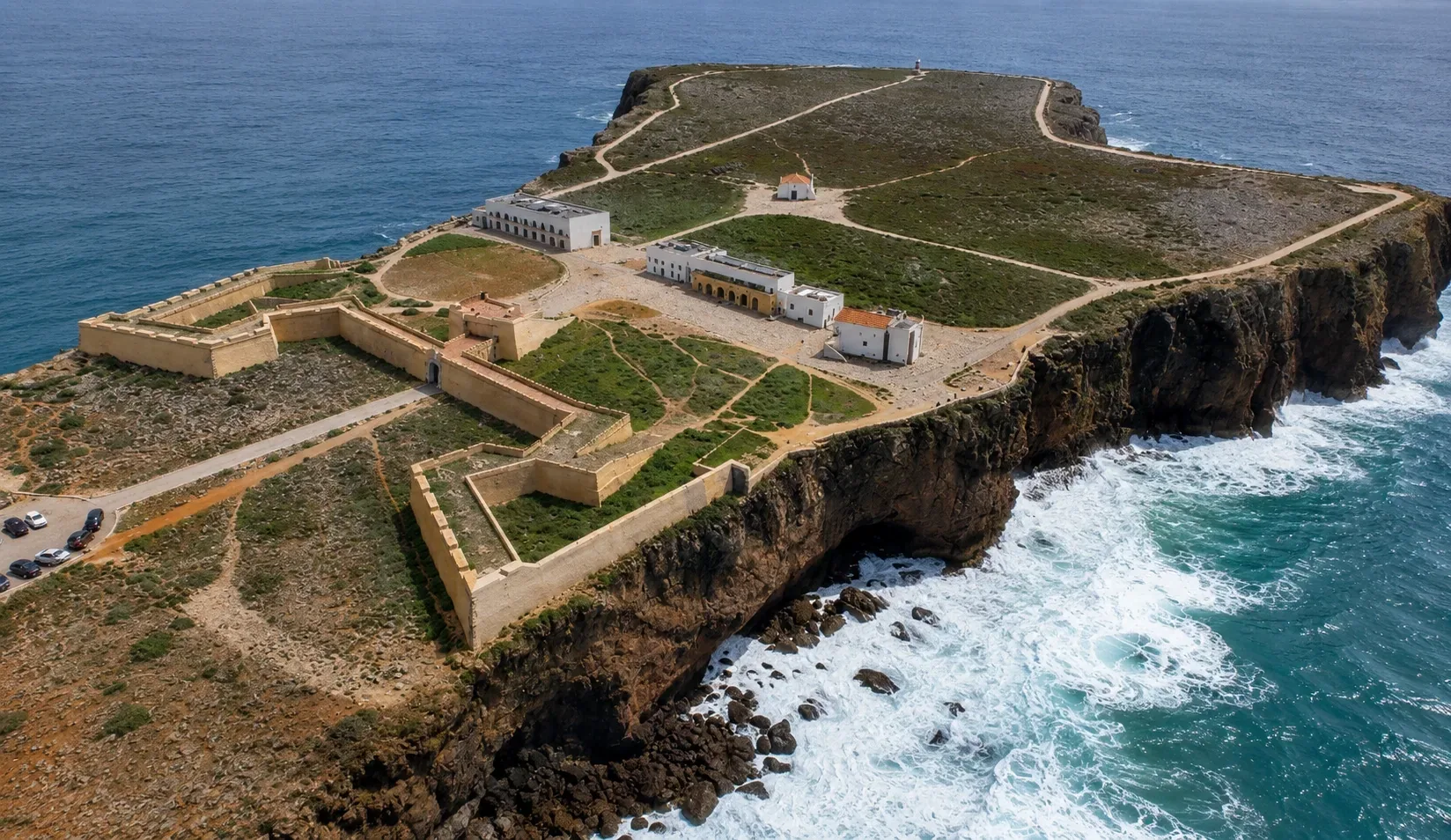 Sagres Fortress on its headland above the Atlantic — the star-shaped fortifications of the Fortaleza de Sagres with the giant 43-metre Rosa dos Ventos wind compass rose on the promontory, associated with Henry the Navigator and the Portuguese Age of Discoveries