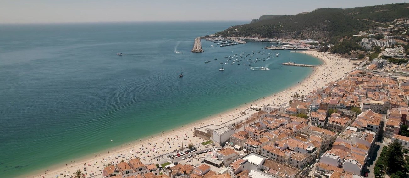 Sesimbra fishing harbour with colourful trawlers and the 17th-century Fort of Santiago on the seafront