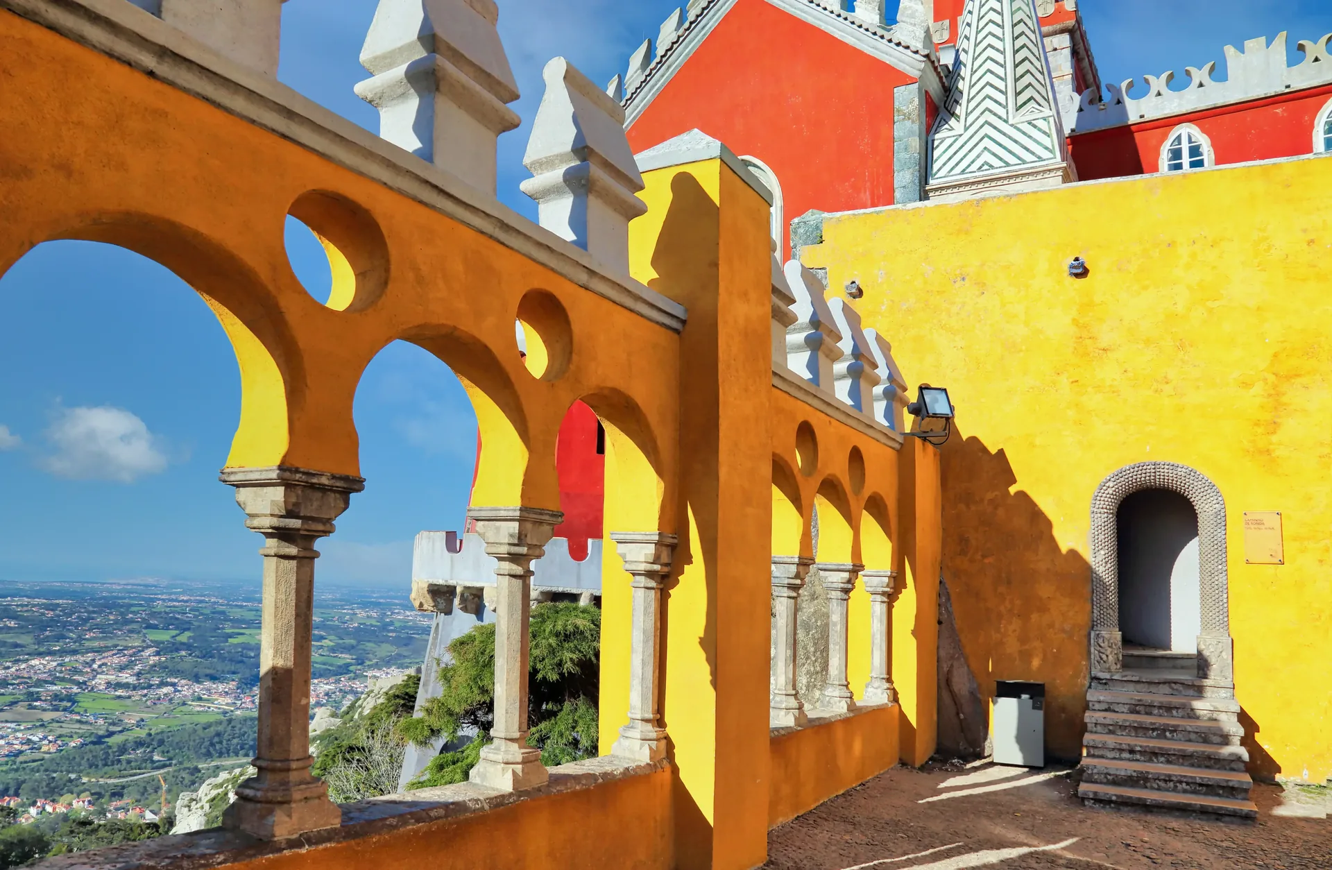 Pena Palace rising above the forested Serra de Sintra — the flamboyant 19th-century Romanticist palace of King Ferdinand II, painted in yellow and terracotta with Manueline towers and battlements, a UNESCO World Heritage Site visited on this private full-day tour from Lisbon