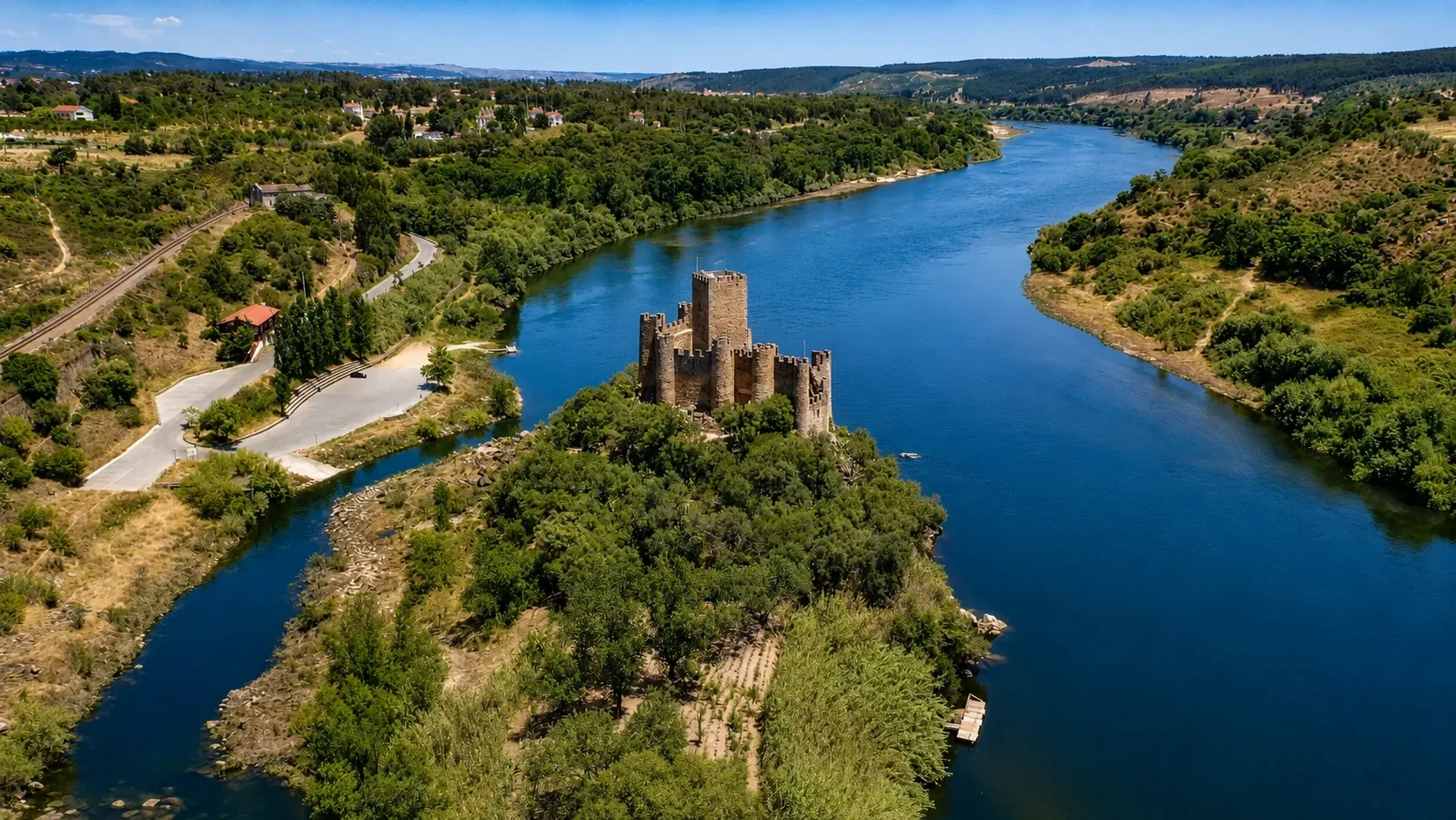 Almourol Castle rising dramatically from its island in the River Tagus — the 12th-century Knights Templar castle with its ten towers and central keep reflected in the calm waters, accessible only by boat, one of the most romantic medieval fortresses in Portugal