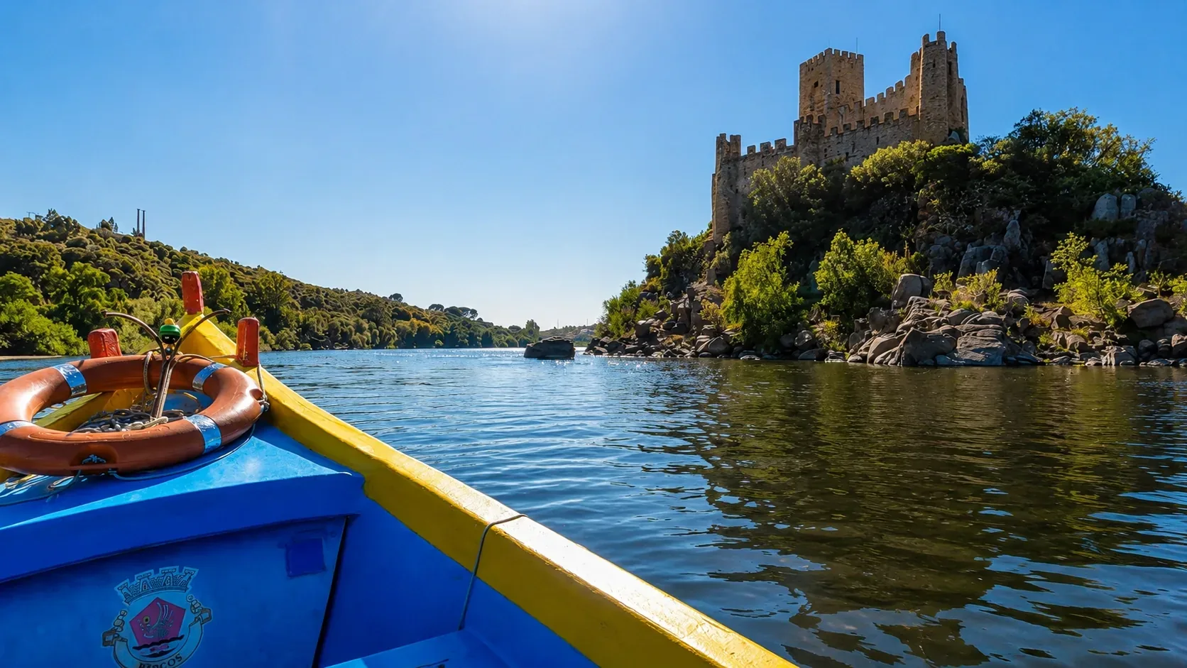 A small boat crossing the River Tagus towards Almourol Castle — the traditional ferry approach to the island fortress, with the dramatic Templar castle growing larger against wooded riverbanks as you cross the calm Tagus waters